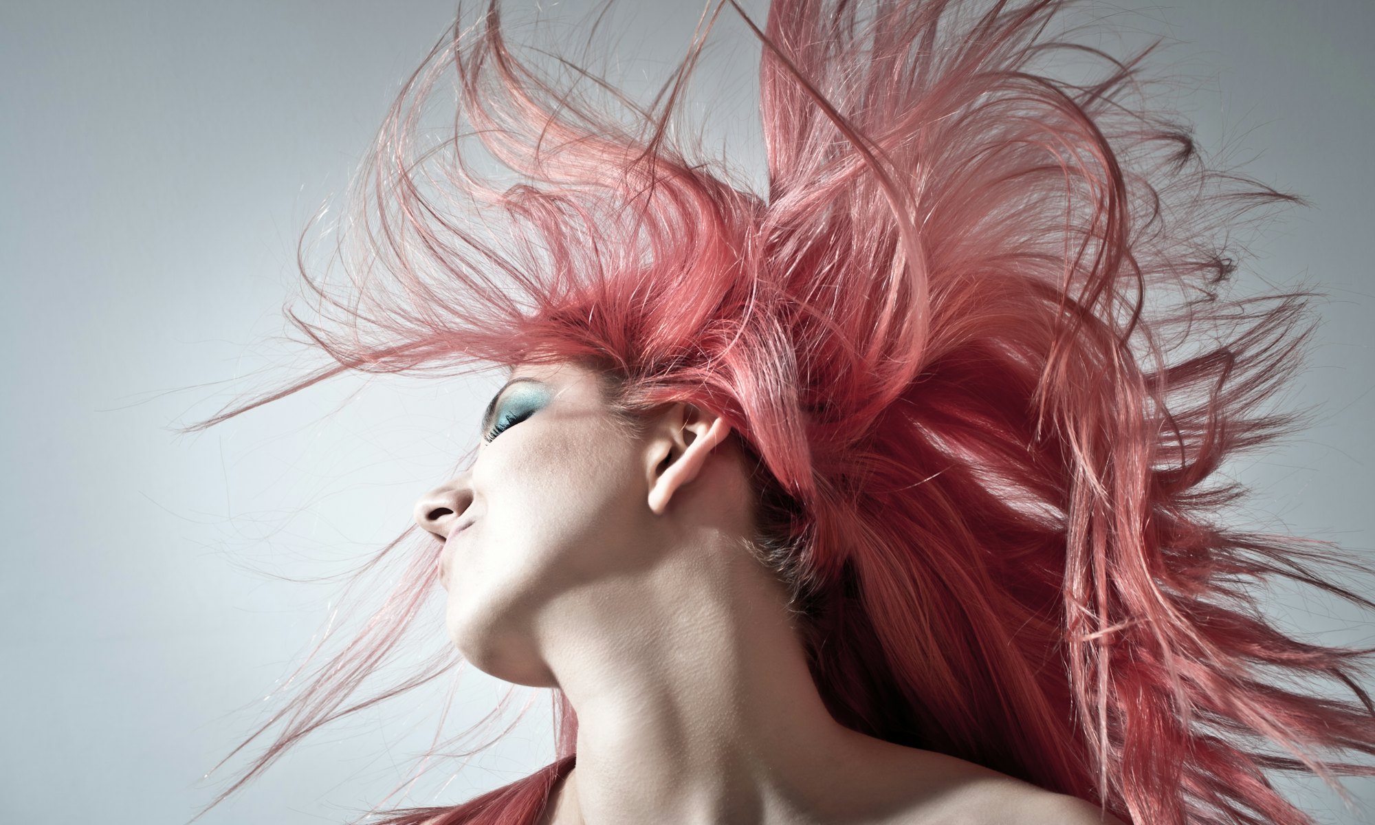 Mujer con melena rosa en movimiento sobre fondo gris claro